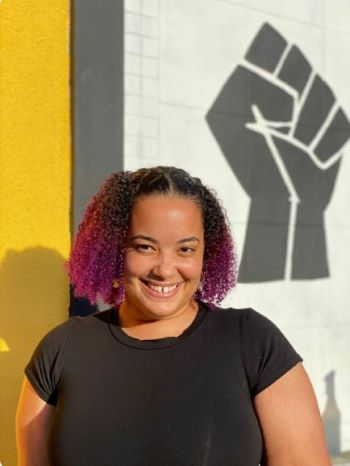 Photo of Harmony Wright with a black solidarity mural in the background.