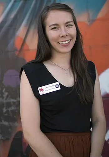 Photo of Tara Francis with a colorful mural in the background.